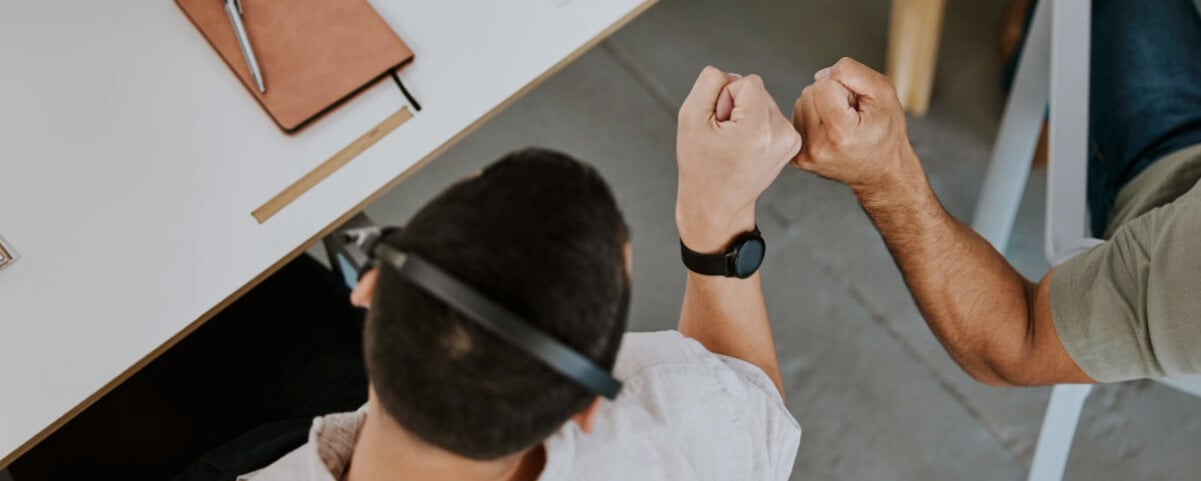 Two sellers fist bumping at their desks